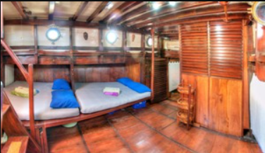A room on a wooden boat with a bed in it.