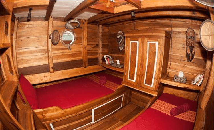 The interior of a wooden boat with two beds.