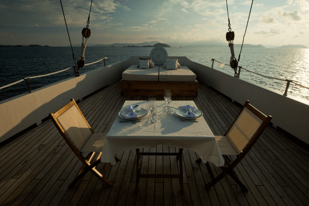 A table and chairs on the deck of a boat.