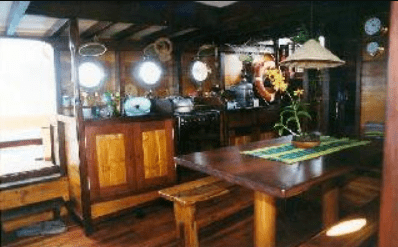 A kitchen on a boat with a table and chairs.