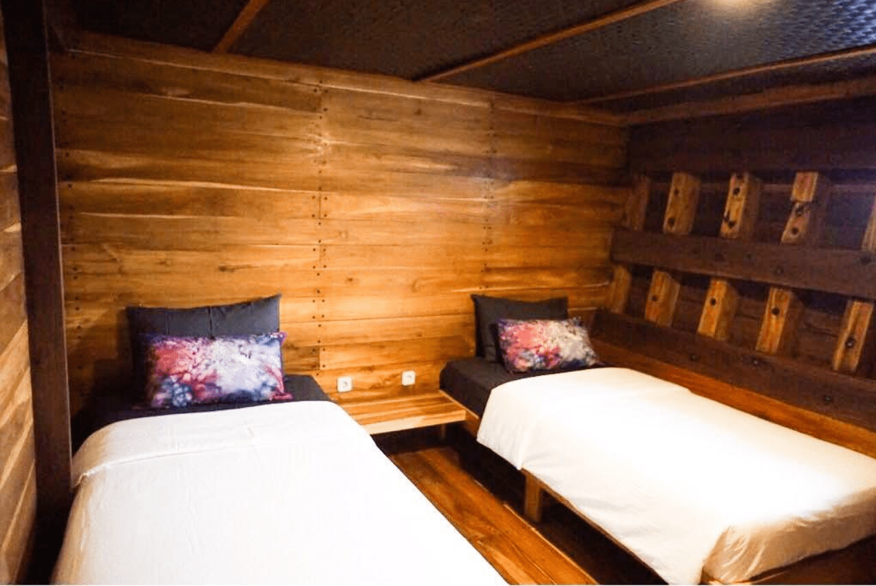 Two beds in a room with wooden walls.