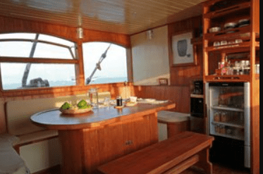 The interior of a wooden boat with a table and chairs.