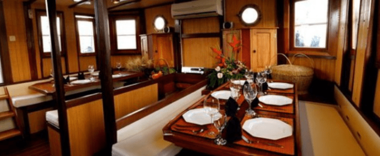 A dining room on a boat with a table and chairs.