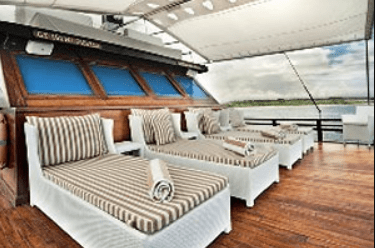 The deck of a boat with lounge chairs on it.