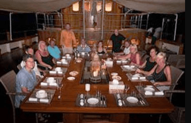 A group of people sitting around a table on a boat.