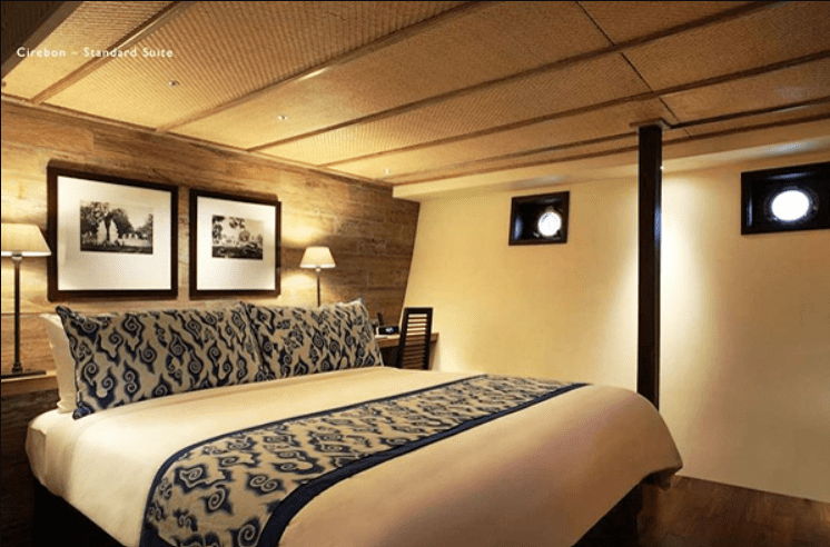 A bedroom on a boat with wooden walls and a bed.