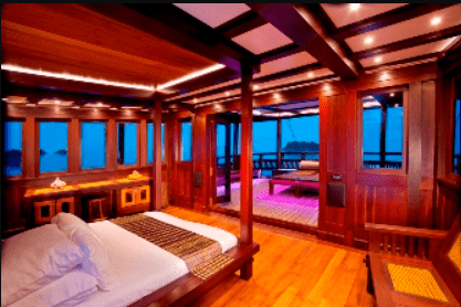 A bedroom on a wooden boat with a view of the ocean.