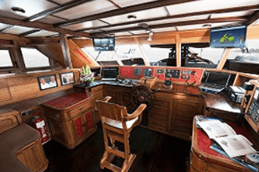 The interior of a wooden boat with a desk and tv.