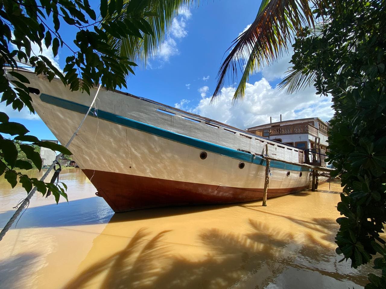 A boat docked in muddy water near a house.