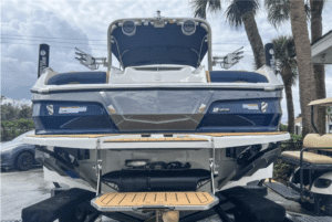 A blue and white 2023 Mastercraft X24 boat parked in a parking lot, available for sale.